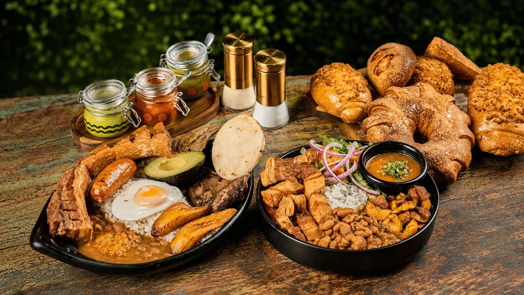 Colombian feast with bandeja paisa, arepas, pastries, and condiments on a rustic table